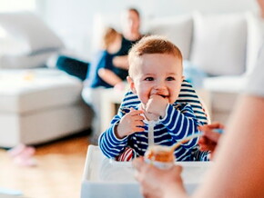 Bebé en su silla comiendo alimentos sólidos