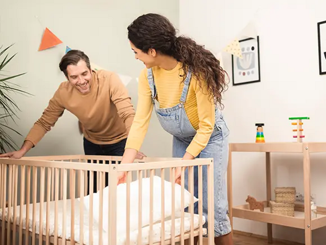 Un hombre y una mujer preparan la cuna del bebé