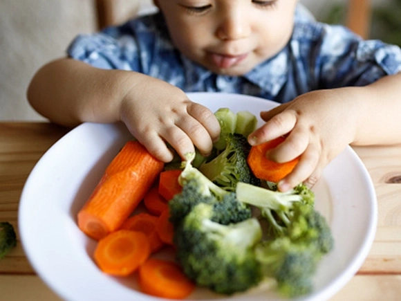 niño comiendo plato de verduras